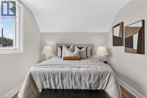 Angled ceiling with a side window, upholstered headboard, and wood-finish flooring - 174 London Street N, Hamilton, ON - Indoor Photo Showing Bedroom