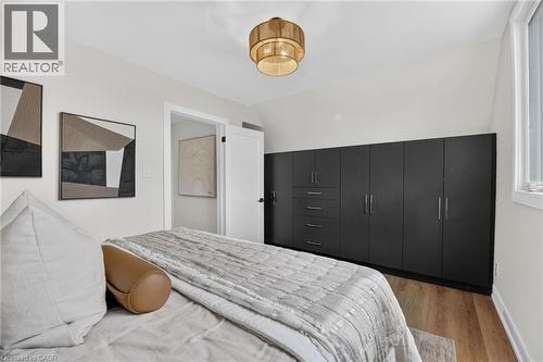 Vaulted ceiling with an overhead light fixture, light wood-finish flooring, and a wall of built-in dark cabinetry featuring multiple doors and drawers - 174 London Street N, Hamilton, ON - Indoor Photo Showing Bathroom