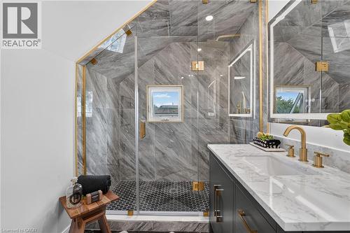 Glass-enclosed shower with gold-tone fixtures and hexagon floor tiles - 174 London Street N, Hamilton, ON - Indoor Photo Showing Bathroom