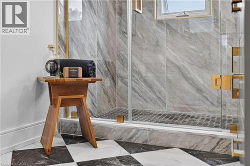 Frameless glass shower enclosure with brass hardware, grey stone-finish wall tile, and black hexagon shower floor tile - 174 London Street N, Hamilton, ON - Indoor Photo Showing Other Room