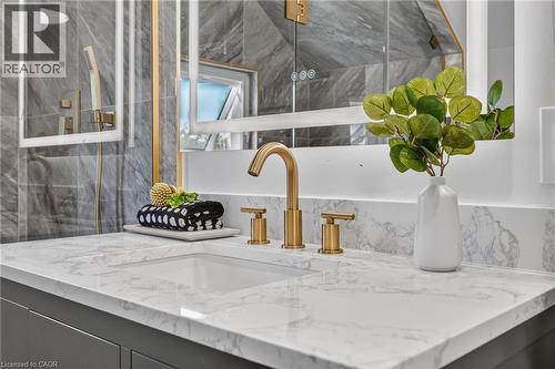 Integrated rectangular sink with a gold-tone widespread faucet, set into a white countertop with gray veining - 174 London Street N, Hamilton, ON - Indoor Photo Showing Other Room