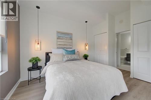 Bedroom featuring wood-finish flooring, two bi-fold closet doors, and recessed lighting - 191 King Street S Unit# 607, Waterloo, ON - Indoor Photo Showing Bedroom