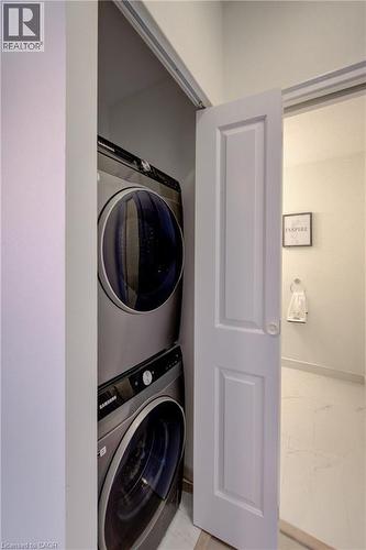Stackable front-loading washer and dryer unit within a dedicated closet - 191 King Street S Unit# 607, Waterloo, ON - Indoor Photo Showing Laundry Room