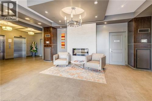 Modern lobby featuring a stacked stone fireplace, a contemporary chandelier, and recessed lighting - 191 King Street S Unit# 607, Waterloo, ON - Indoor Photo Showing Other Room