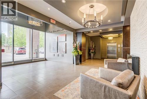 Spacious lobby featuring large format tile flooring, a circular recessed ceiling with a chandelier, floor-to-ceiling windows, and elevator access - 191 King Street S Unit# 607, Waterloo, ON - Indoor Photo Showing Other Room