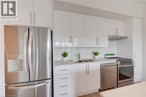 Modern kitchen featuring white cabinetry, a stainless steel refrigerator, a stainless steel dishwasher, a stainless steel range, and a dual basin sink - 191 King Street S Unit# 607, Waterloo, ON - Indoor Photo Showing Kitchen With Stainless Steel Kitchen With Double Sink
