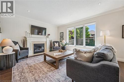 Living area featuring a gas fireplace with a stone surround, white mantel, and wood-finish flooring. - 828 Copper Ridge Drive, Waterloo, ON - Indoor Photo Showing Living Room With Fireplace