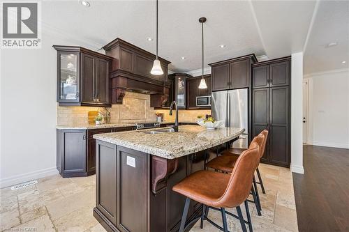 Kitchen featuring dark wood cabinetry, a granite countertop island, stainless steel appliances, recessed lighting, and tile flooring. - 828 Copper Ridge Drive, Waterloo, ON - Indoor Photo Showing Kitchen With Double Sink With Upgraded Kitchen
