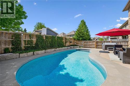 Curved inground pool with surrounding concrete patio. - 828 Copper Ridge Drive, Waterloo, ON - Outdoor With In Ground Pool With Backyard