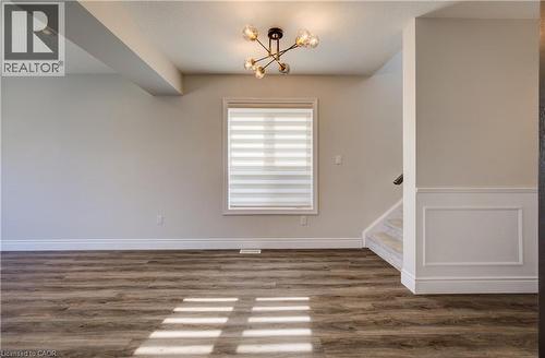 Room featuring wood-finish flooring, a contemporary chandelier, recessed ceiling lighting, a window with horizontal blinds, and a staircase with carpeted treads - 80 Miranda Path, Elmira, ON - Indoor Photo Showing Other Room