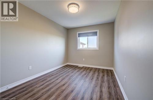Neutral toned interior room featuring wood-finish flooring, white baseboards, and a single window with a roller shade - 80 Miranda Path, Elmira, ON - Indoor Photo Showing Other Room