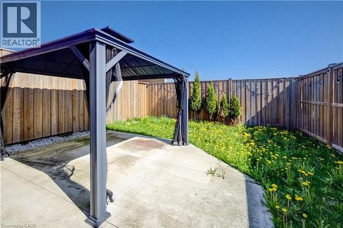 Patio area with a dark-framed gazebo, concrete slab, and wood privacy fencing - 80 Miranda Path, Elmira, ON - Outdoor