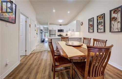 Open-concept dining area featuring wood-finish flooring, recessed lighting, and a kitchen with white cabinetry and stainless steel appliances - 16 Steed Court, Brantford, ON 