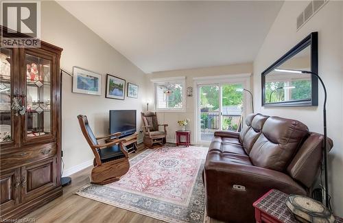 Vaulted ceiling, wood-finish flooring, sliding glass door, multiple windows, and a built-in display cabinet - 16 Steed Court, Brantford, ON 
