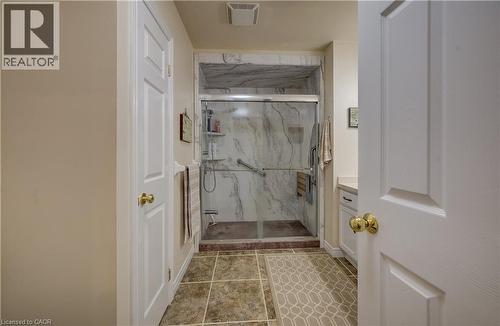 Tiled flooring, walk-in shower with glass enclosure, integrated shelving, and support bars, vanity with countertop - 16 Steed Court, Brantford, ON 