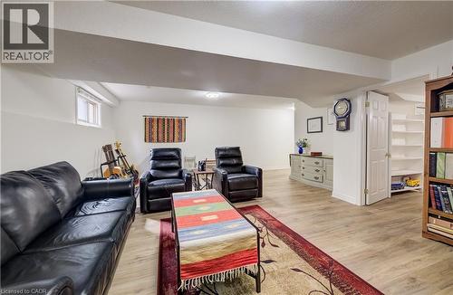 Spacious room featuring wood-finish flooring, recessed lighting, a built-in shelving unit, a window, and a white paneled door - 16 Steed Court, Brantford, ON 