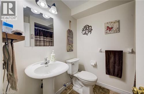 Pedestal sink with chrome faucet, white toilet, and tile-look flooring - 16 Steed Court, Brantford, ON 