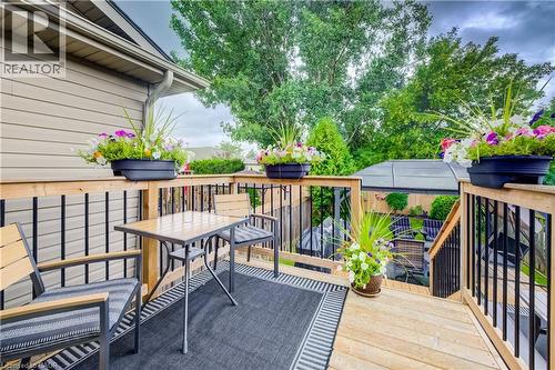 Rear deck with natural wood decking and black metal railings, featuring stairs to lower level - 16 Steed Court, Brantford, ON 