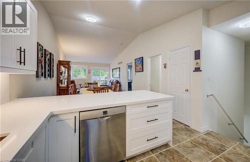 Kitchen island with white cabinetry, stainless steel dishwasher, and white countertops - 16 Steed Court, Brantford, ON 