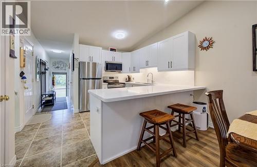 Kitchen featuring white cabinetry, stainless steel appliances, a breakfast bar, and wood-finish flooring - 16 Steed Court, Brantford, ON 