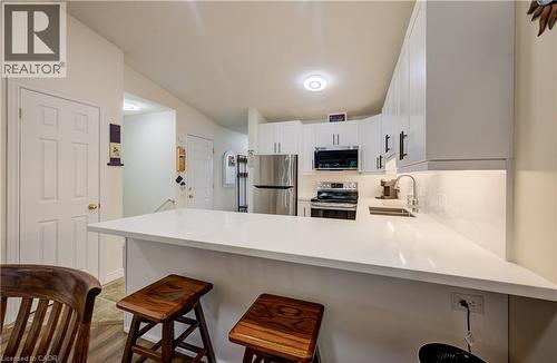 Kitchen featuring white cabinetry, stainless steel appliances, a white countertop peninsula, and an undermount sink - 16 Steed Court, Brantford, ON 