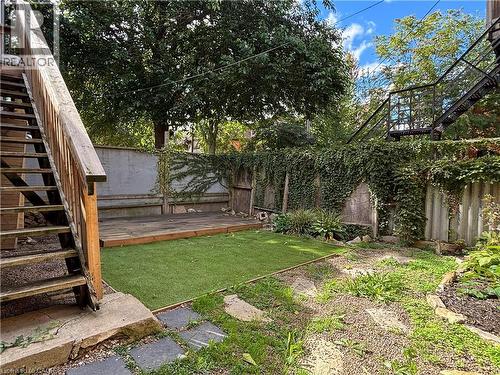 Outdoor shared space featuring a wood deck, artificial turf, and stepping stones - 76 Wentworth Street S, Hamilton, ON 