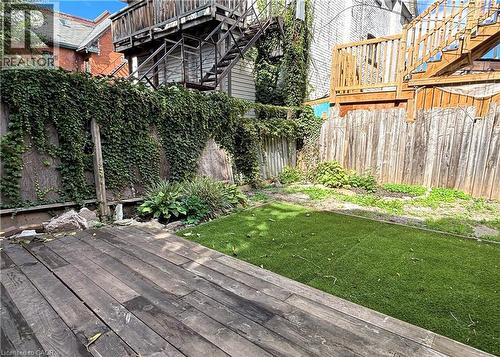Backyard shared space featuring a wood-finish deck and green artificial turf - 76 Wentworth Street S, Hamilton, ON 