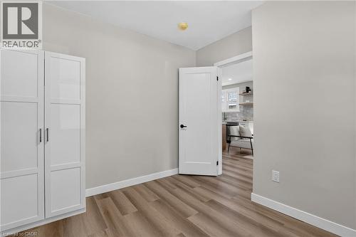 Wood-finish flooring, white built-in cabinetry with modern hardware, and a white interior door with matte black hardware - 43 E Brucedale Avenue E, Hamilton, ON 