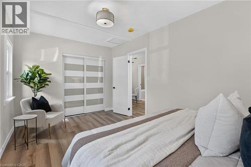 Wood-finish flooring, white trim, sliding closet doors with frosted panels, and a drum pendant light fixture - 43 E Brucedale Avenue E, Hamilton, ON 
