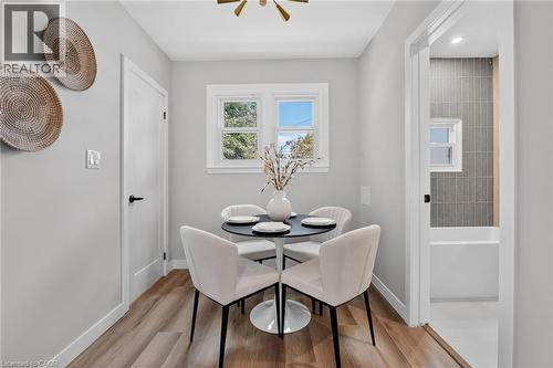 Wood-finish flooring, white interior doors with black hardware, double casement windows, and a bathroom featuring vertical subway tile - 43 E Brucedale Avenue E, Hamilton, ON 