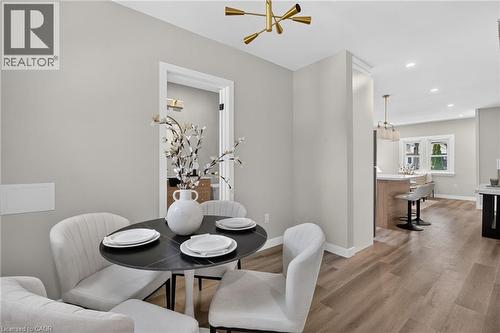 Wood-finish flooring, recessed lighting, contemporary ceiling light fixture, doorway with white trim, and a built-in kitchen island with a light-toned countertop - 43 E Brucedale Avenue E, Hamilton, ON 