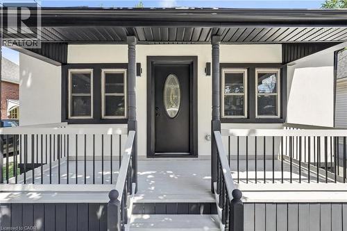 Covered front porch with black railings, decorative porch columns, and a black front door with oval-shaped glass insert - 43 E Brucedale Avenue E, Hamilton, ON 