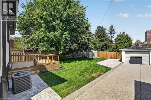 Expansive backyard featuring a multi-level wood deck, manicured lawn, concrete patio, and detached garage - 43 E Brucedale Avenue E, Hamilton, ON 