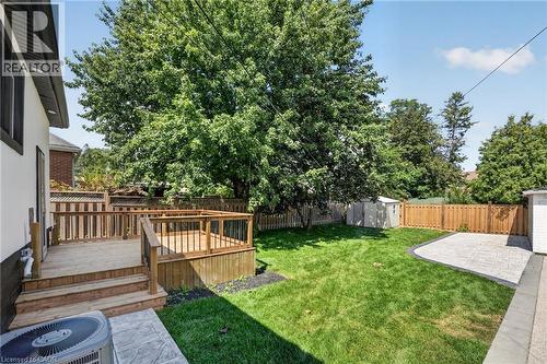 Expansive backyard featuring a multi-level wood deck, manicured lawn, and a stamped concrete patio - 43 E Brucedale Avenue E, Hamilton, ON 