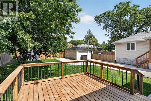 Expansive wood deck with metal balusters, surrounded by a green lawn and mature trees - 43 E Brucedale Avenue E, Hamilton, ON 