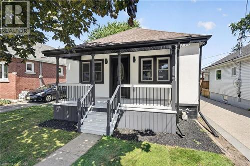 Inviting front porch with a dark wood railing, white steps, and a dark wood porch ceiling - 43 E Brucedale Avenue E, Hamilton, ON 