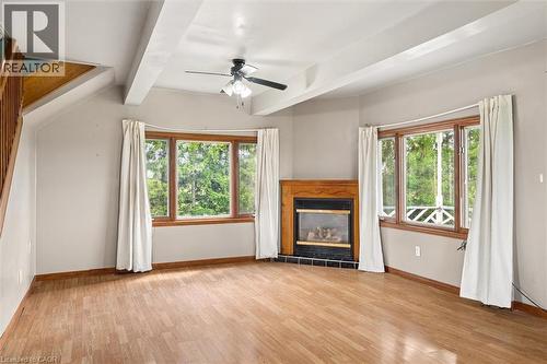 Wood-finish flooring, wood-framed bay window, wood staircase, ceiling fan, and fireplace with a wood mantle and tile surround - 5480 Line 42 Line, Mitchell, ON 