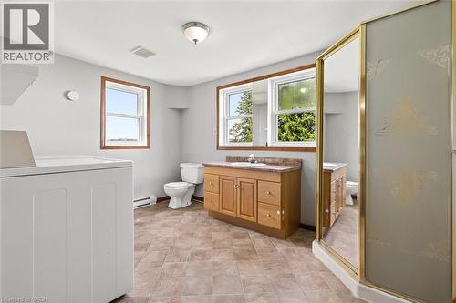 Spacious bathroom featuring a wood-finish vanity with a stone-finish countertop, a toilet, and a stand-up shower with a gold-tone frame - 5480 Line 42 Line, Mitchell, ON 