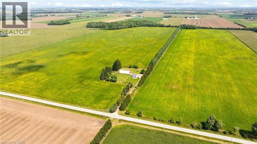 Expansive green fields with a visible residential structure, bordered by a paved road - 5480 Line 42 Line, Mitchell, ON 