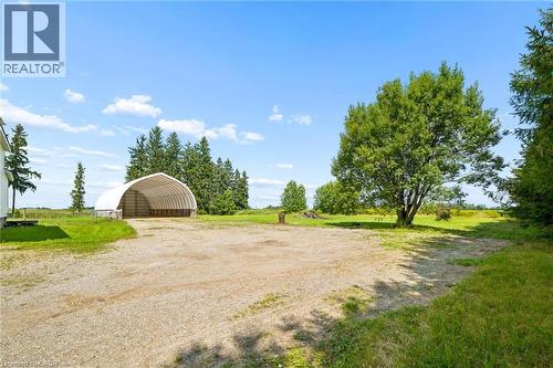 Spacious gravel drive with open-sided storage structure, surrounded by mature trees and expansive grass areas - 5480 Line 42 Line, Mitchell, ON 
