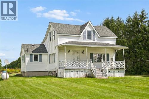 Two-story residence featuring white siding, a covered front porch with decorative railings, and a dormer window - 5480 Line 42 Line, Mitchell, ON 