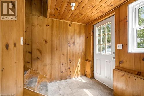 Wood-paneled room featuring a white paneled door with windowpanes, a square window, and light-toned floor tiles - 5480 Line 42 Line, Mitchell, ON 