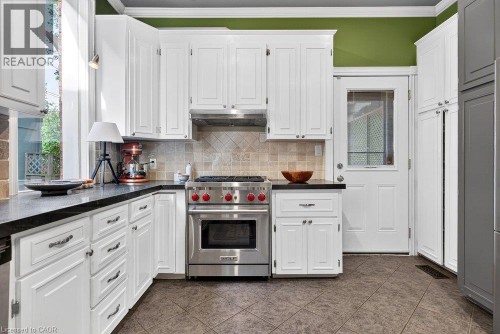 White cabinetry with dark countertops, stainless steel range and hood, tiled backsplash, and patterned floor tiles - 16 Bruce Street, Hamilton, ON 