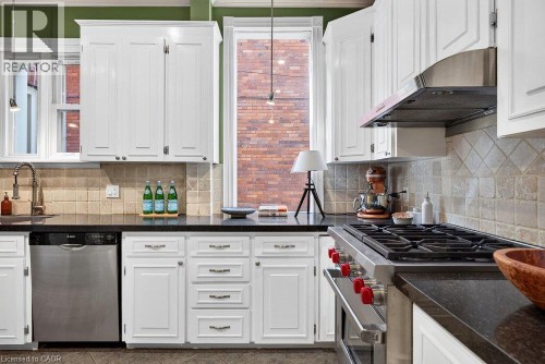 White cabinetry with dark countertops, stainless steel appliances, and a tiled backsplash - 16 Bruce Street, Hamilton, ON 