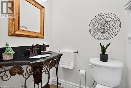 Pedestal vanity with wrought iron base, dark countertop, and copper-toned faucet - 16 Bruce Street, Hamilton, ON 