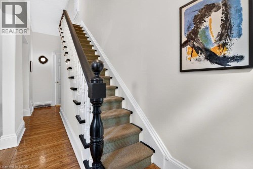 Hardwood flooring, painted white walls, black-stained newel posts, white balusters, and carpeted stair treads - 16 Bruce Street, Hamilton, ON 