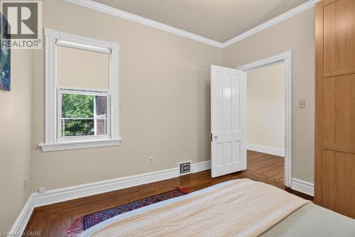 Hardwood flooring, crown molding, white trim, wood-finish built-in cabinetry, and a multi-pane window - 16 Bruce Street, Hamilton, ON 