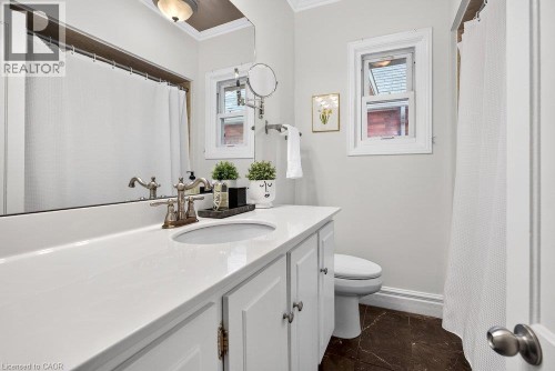 White vanity with a single basin, white countertop, and antique brass finish faucet - 16 Bruce Street, Hamilton, ON 