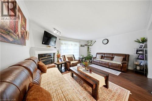 Living area featuring wood-finish flooring, a decorative fireplace with a mantel, and track lighting - 384 Limeridge Road E Unit# 16, Hamilton, ON 