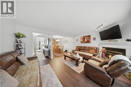 Wood-finish flooring throughout, featuring a fireplace with a white mantel and dark surround, recessed lighting, and a track lighting fixture - 384 Limeridge Road E Unit# 16, Hamilton, ON 